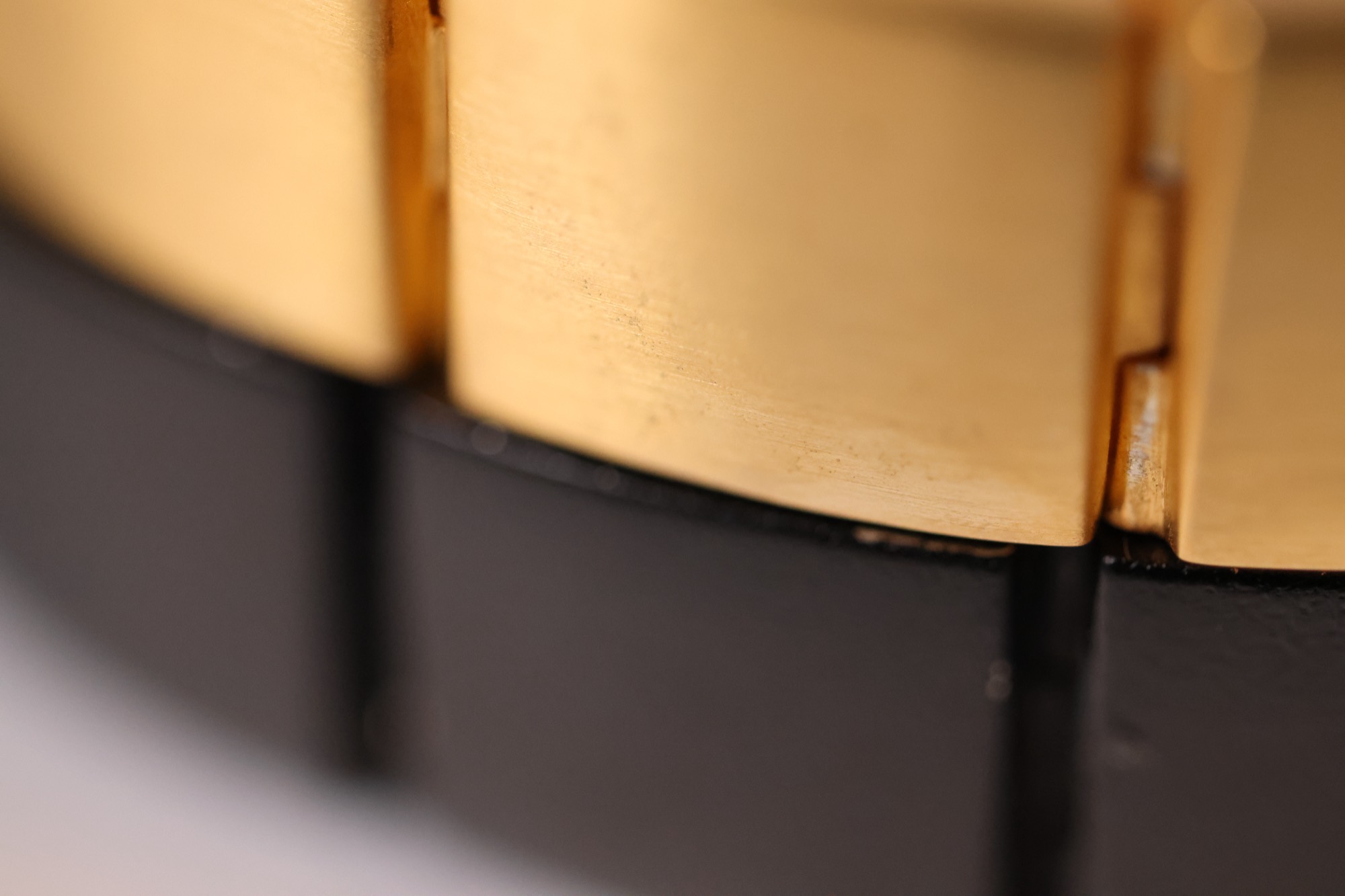 Macro detail of the Vitul Sol and Onyx bracelets stacked, brushed gold above black titanium